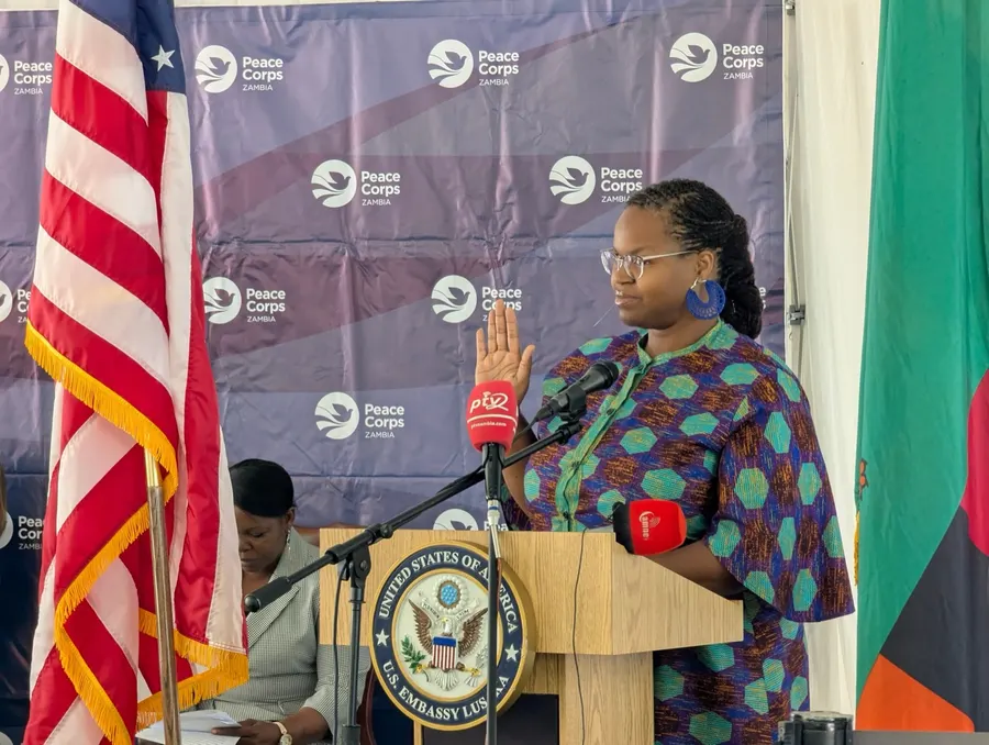 Natalie administering the Volunteer pledge at the U.S. Embassy in Lusaka, beside the American and Zambian flags